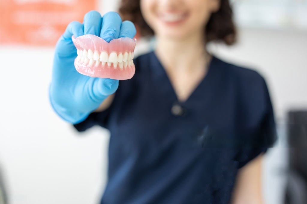A dentist holding a set of custom dentures at Victor Crescent Dental Clinic in Narre Warren, providing natural-looking and comfortable tooth replacement options for all ages.