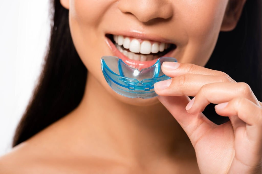 A patient smiling while holding a custom mouthguard before fitting at Victor Crescent Dental Clinic in Narre Warren, offering protection for sports and nighttime use.
