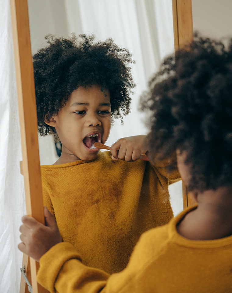 A young child brushing their teeth while looking in the mirror, practicing good oral hygiene habits taught at Victor Crescent Dental Clinic in Narre Warren.