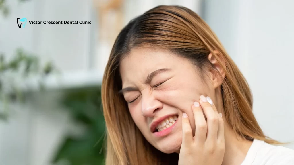 Close-up of a young woman clenching her jaw and holding her cheek in pain, illustrating the effects of stress-related teeth grinding (bruxism) and TMJ issues. Seek relief from your Dentist in Berwick.